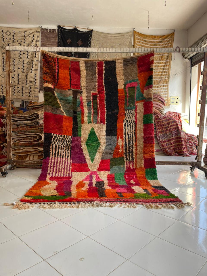 Lifestyle shot of a colorful Moroccan rug with geometric patterns and fringe edges.