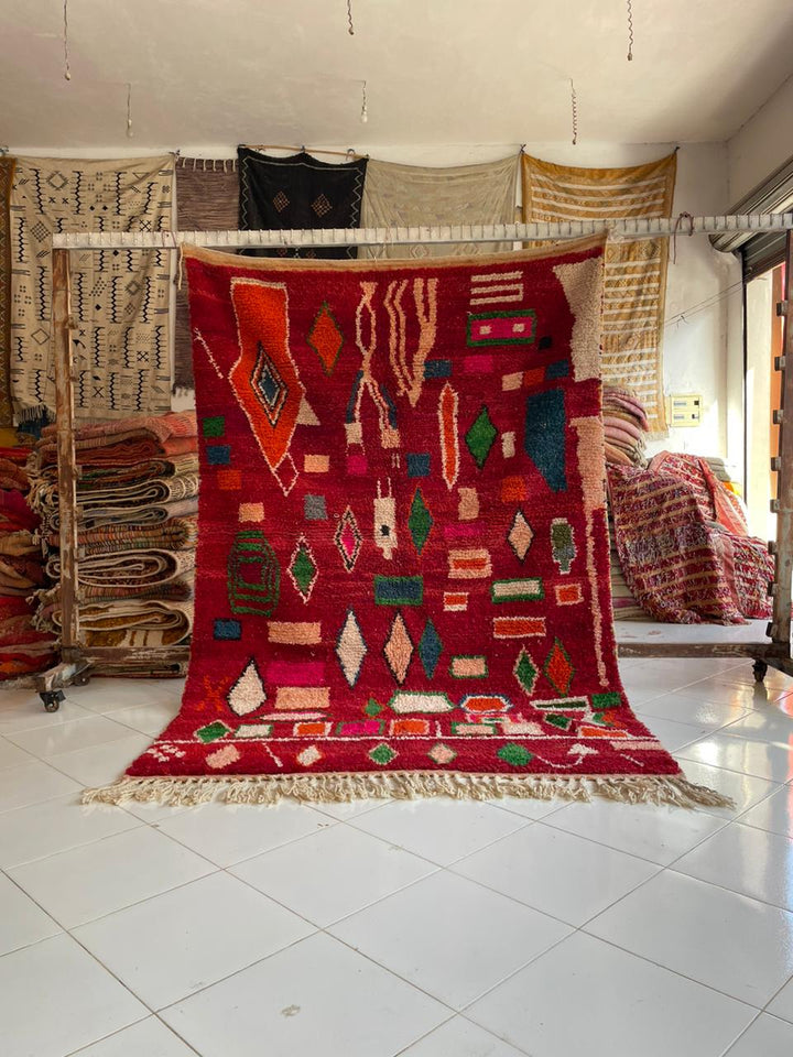 Lifestyle shot of a colorful Moroccan rug with geometric patterns and fringe edges.