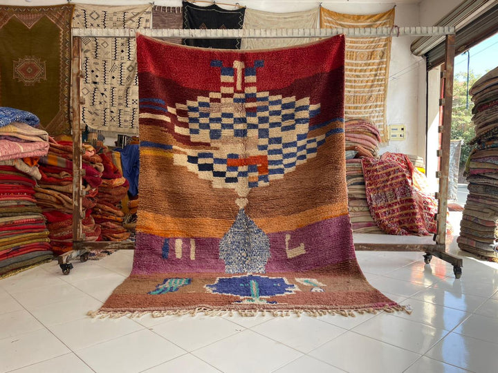 Lifestyle shot of a vintage Moroccan rug with geometric patterns in brown, red, and blue.
