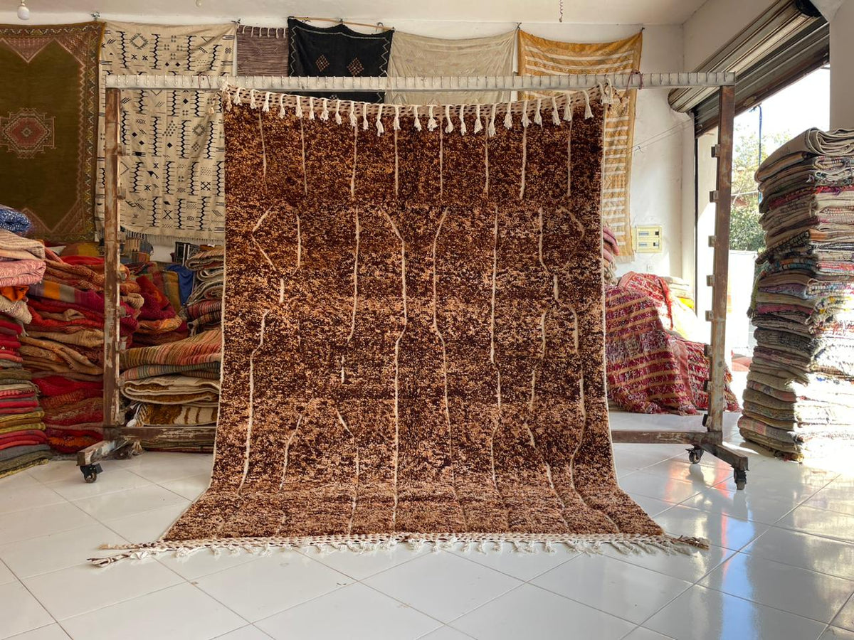 Lifestyle shot of a brown tufted Beni Ourain rug with geometric pattern on a natural background.