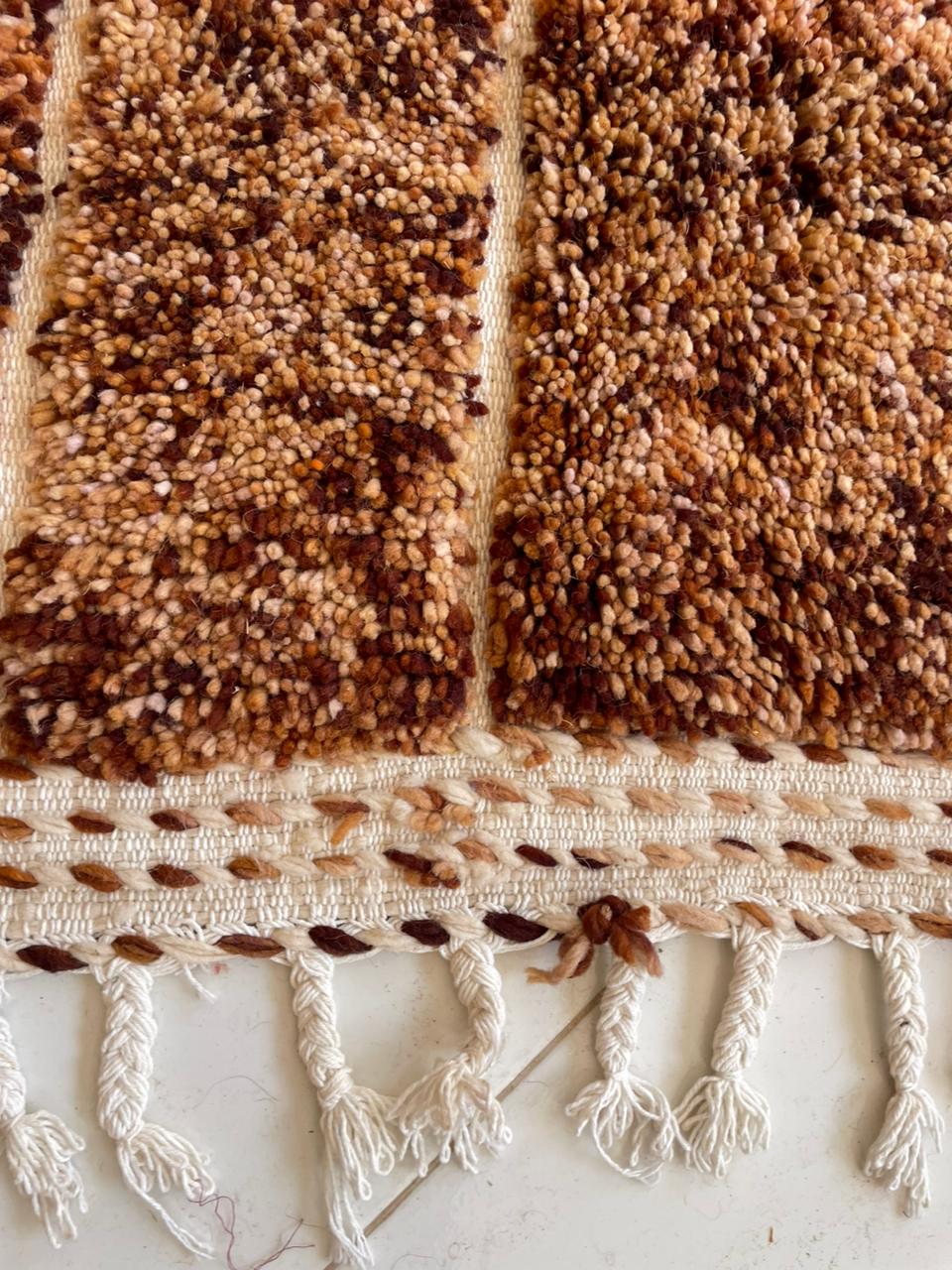 Detail close-up of a brown tufted Beni Ourain rug featuring fringe detail.