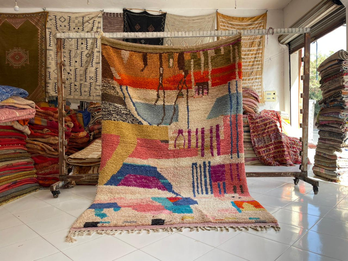 Lifestyle shot of a colorful Berber rug featuring geometric patterns and fringe edges.