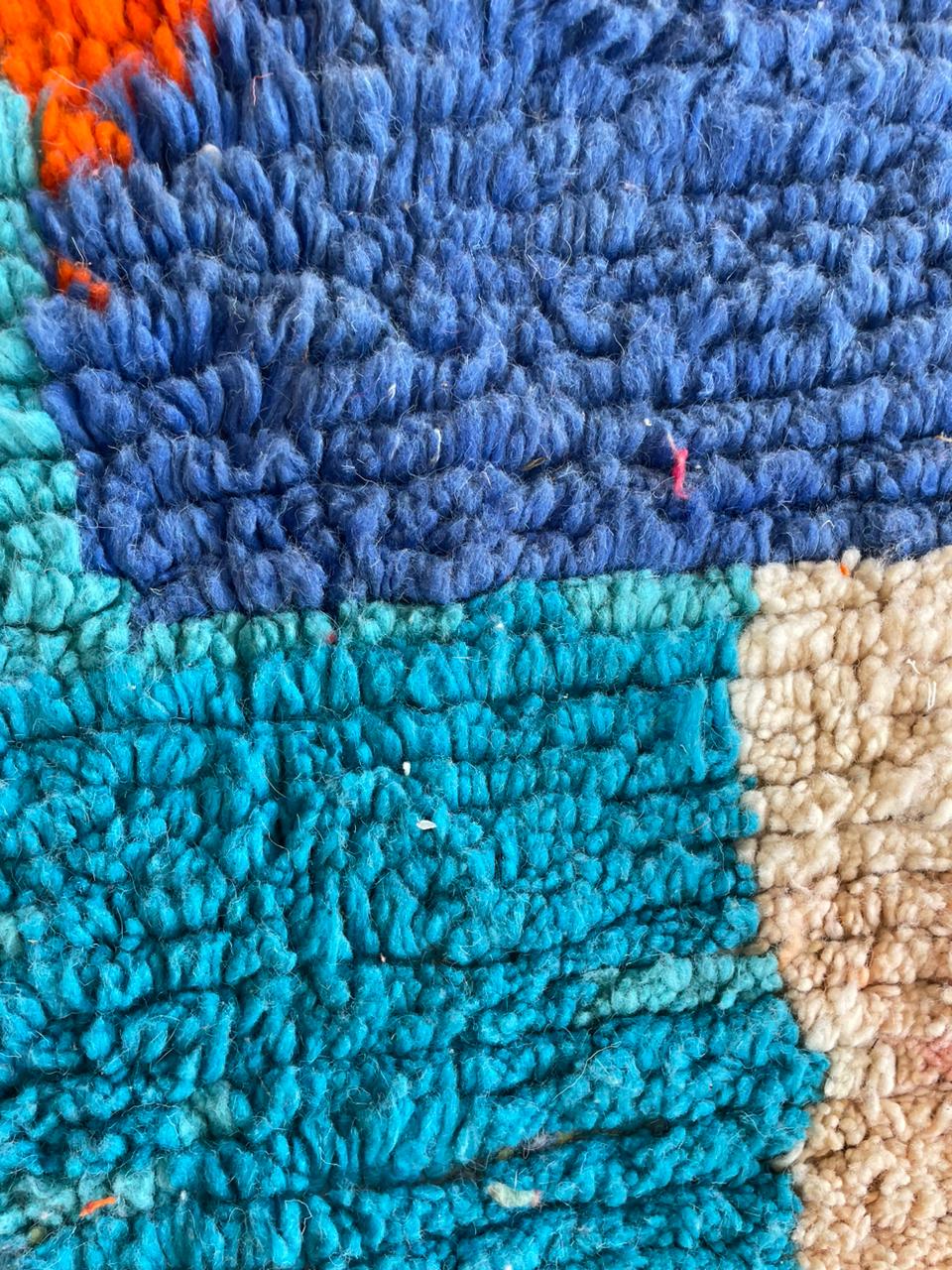Detail close-up of a colorful Berber rug featuring geometric patterns and a textured weave.