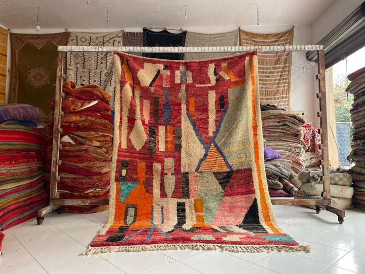 Lifestyle shot of a colorful Moroccan rug with geometric patterns in red, orange, and blue.