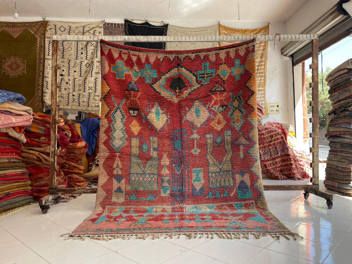 Lifestyle shot of a colorful Berber rug with geometric patterns in red, blue, and beige.