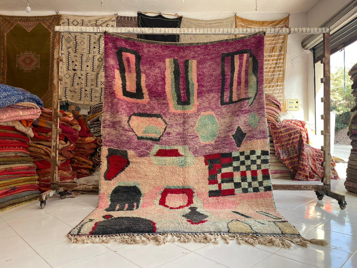Lifestyle shot of a colorful Moroccan rug with geometric patterns in purple and pink.