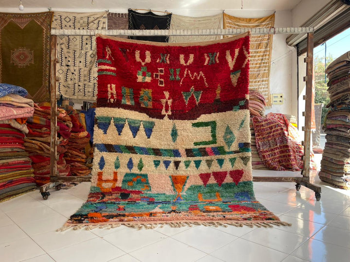 Lifestyle shot of a colorful green and red Moroccan rug with geometric patterns.