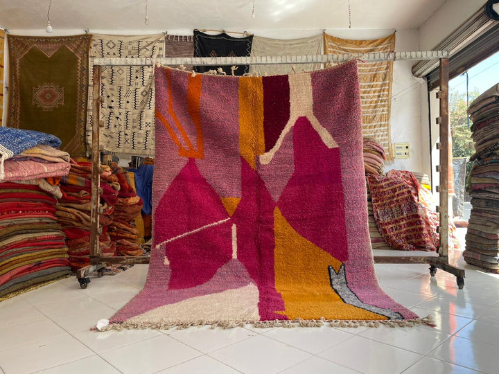 Lifestyle shot of a colorful pink Moroccan rug with geometric patterns in a natural setting.