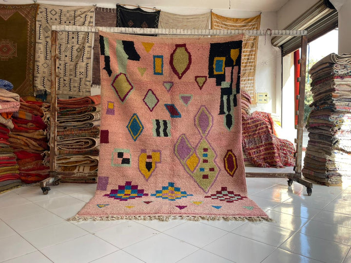 Lifestyle shot of a faded pink Moroccan rug with geometric patterns in a natural setting.