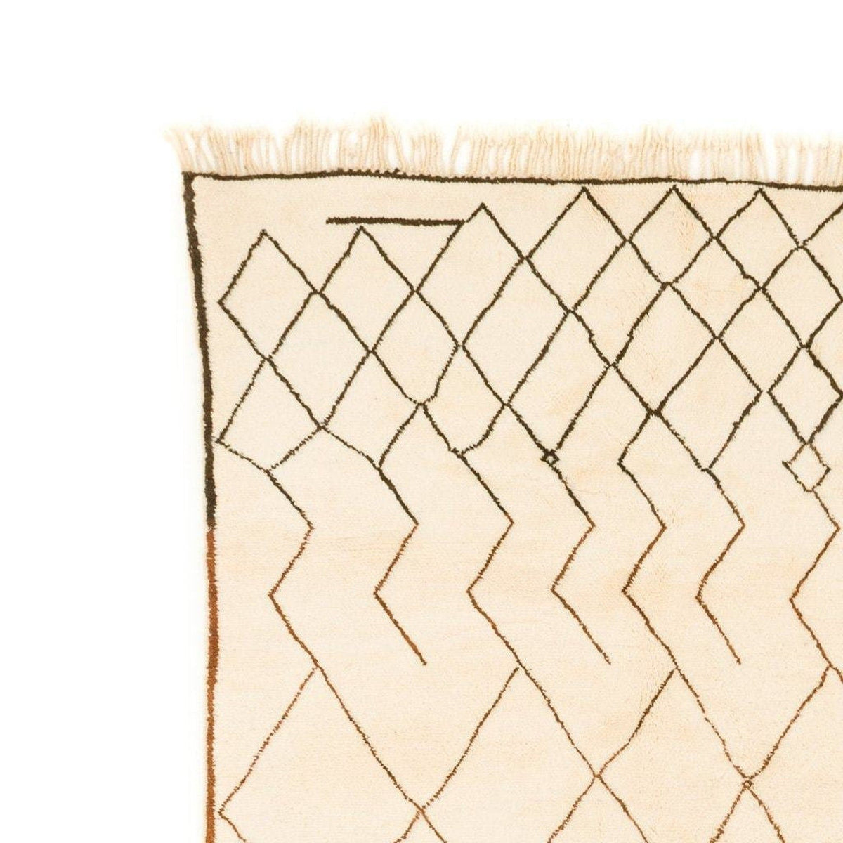 Close-up detail of the edge of a beige and brown Beni Ourain rug featuring a diamond pattern and fringe edge.