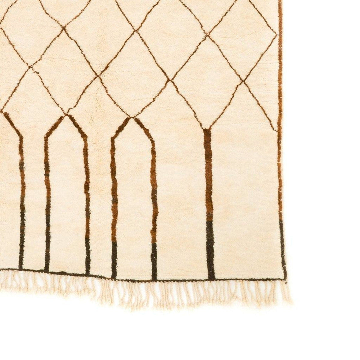 Close-up detail of a large beige and brown Moroccan rug showcasing geometric patterns and fringe edges.