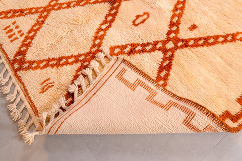 Close-up detail of a beige and brown Beni Ourain rug highlighting the diamond design and fringe.