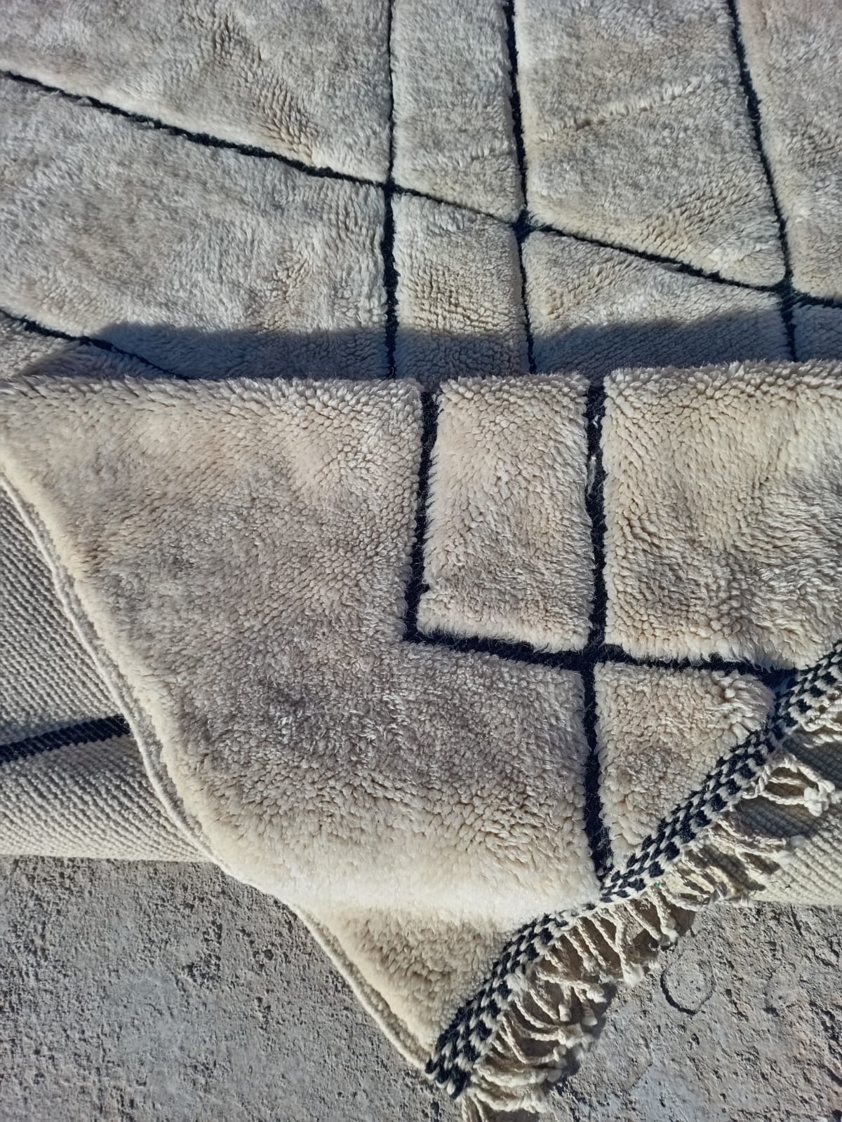 Close-up detail of a white Moroccan rug featuring a tufted texture and geometric patterns.