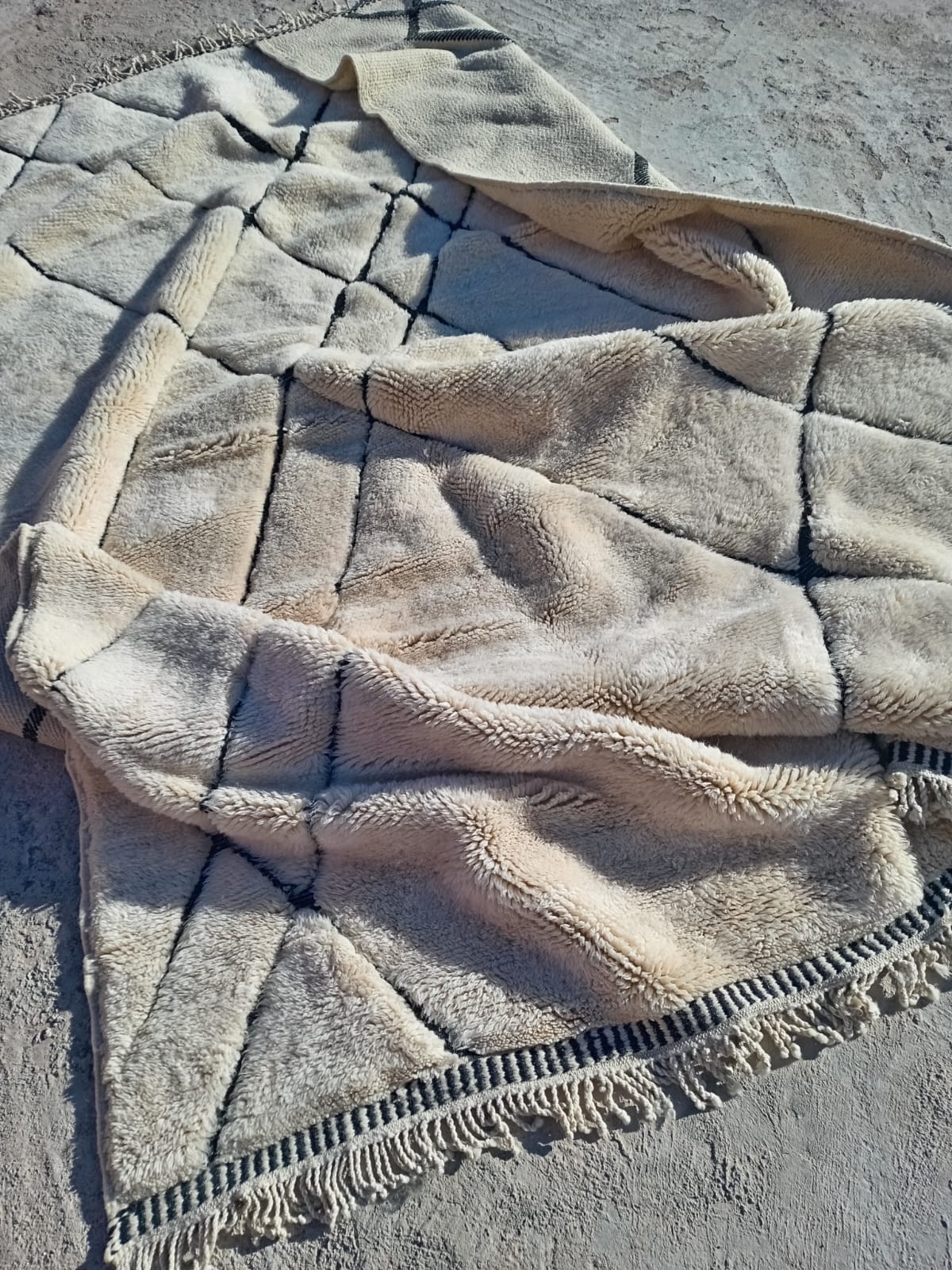 Close-up detail of a white Moroccan rug featuring a tufted texture and geometric patterns.