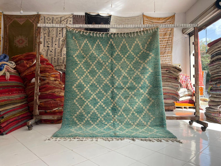 Lifestyle shot of a turquoise Berber rug with geometric patterns and fringed edges.