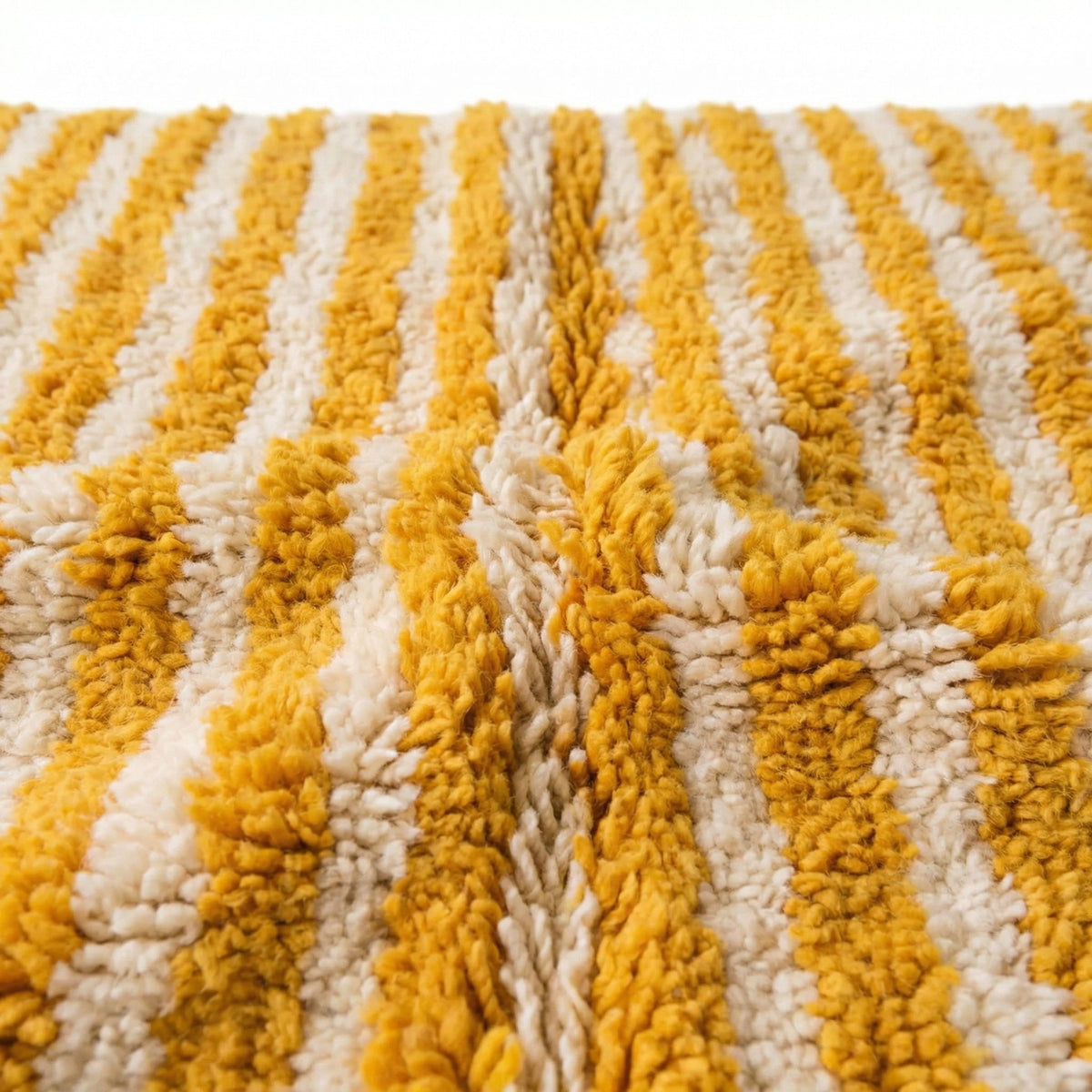 Close-up detail of the textured edge of a mustard rug with fringe detail.