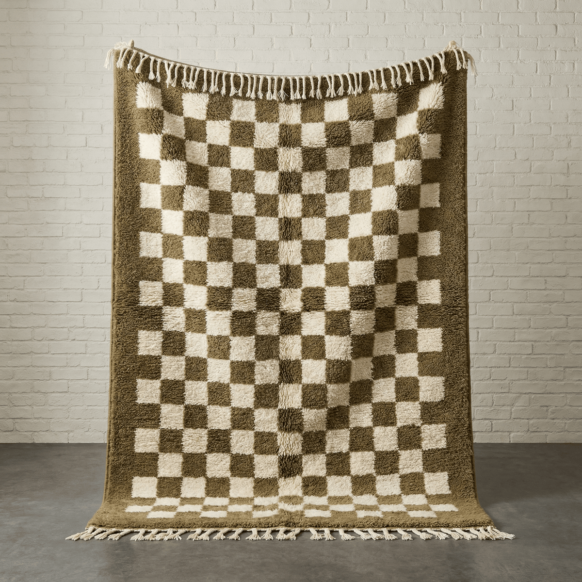 Lifestyle view of the olive green checkered rug with fringe edges on a natural background.