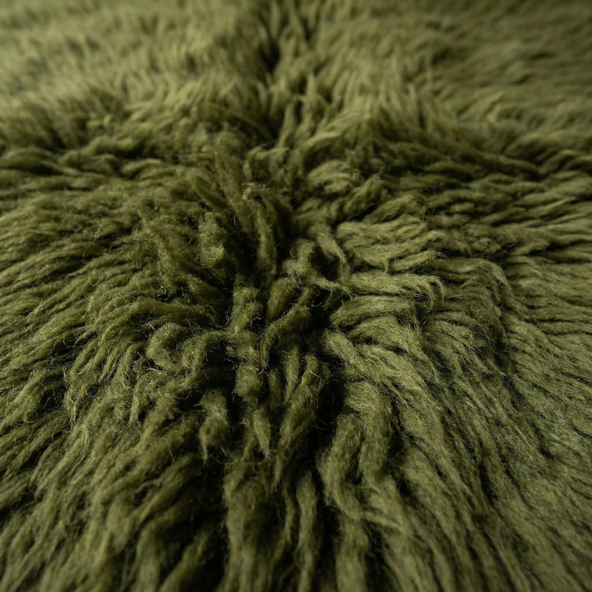 Detail close-up of the olive green Moroccan rug emphasizing its textured surface and soft fibers.