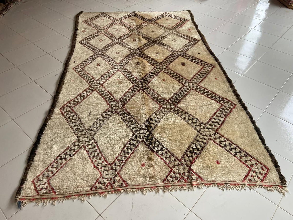 Front view of a vintage Moroccan rug with fringed edges and a geometric pattern in beige and brown.