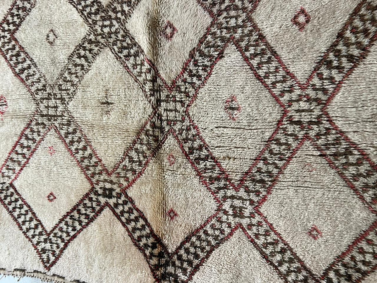Detail view of a vintage Moroccan rug featuring a diamond pattern in beige and brown.