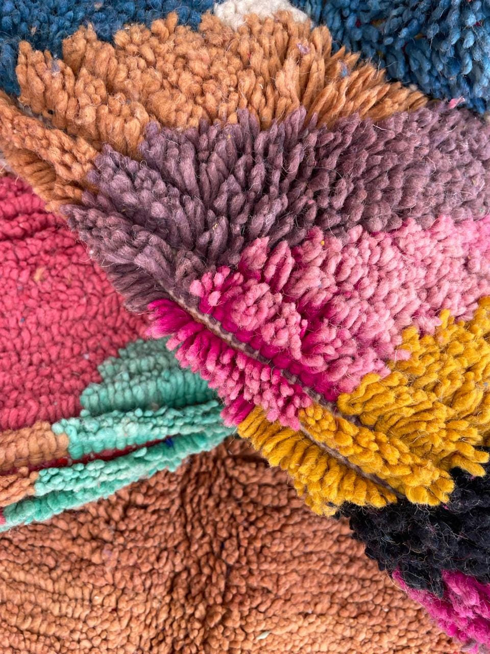 Detail close-up of a vintage Moroccan rug featuring a colorful design in pink, brown, and yellow.