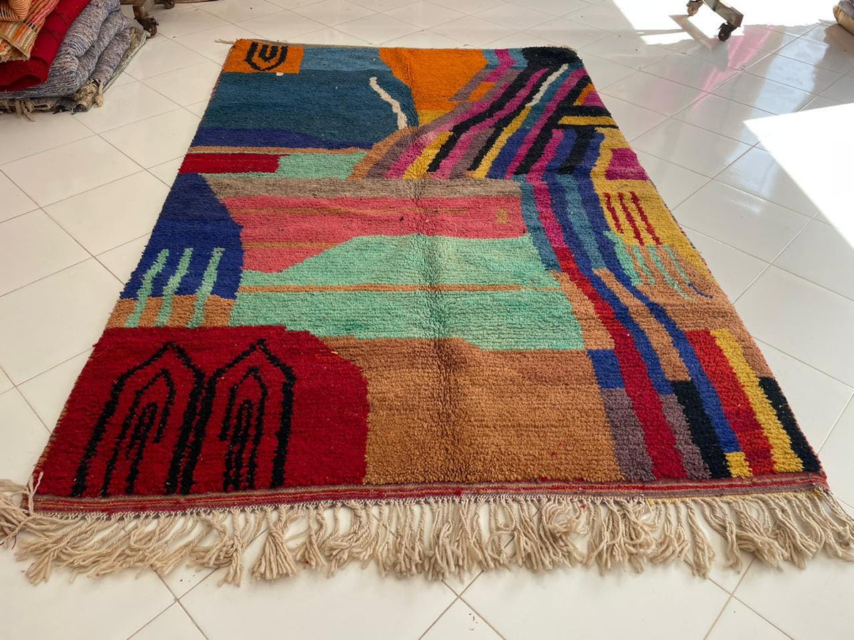 Top view of a vintage Moroccan rug featuring colorful tribal patterns in blue, orange, and red.