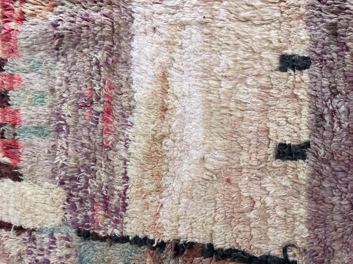 Detail shot of a vintage Moroccan rug with tribal patterns in beige and brown colors.