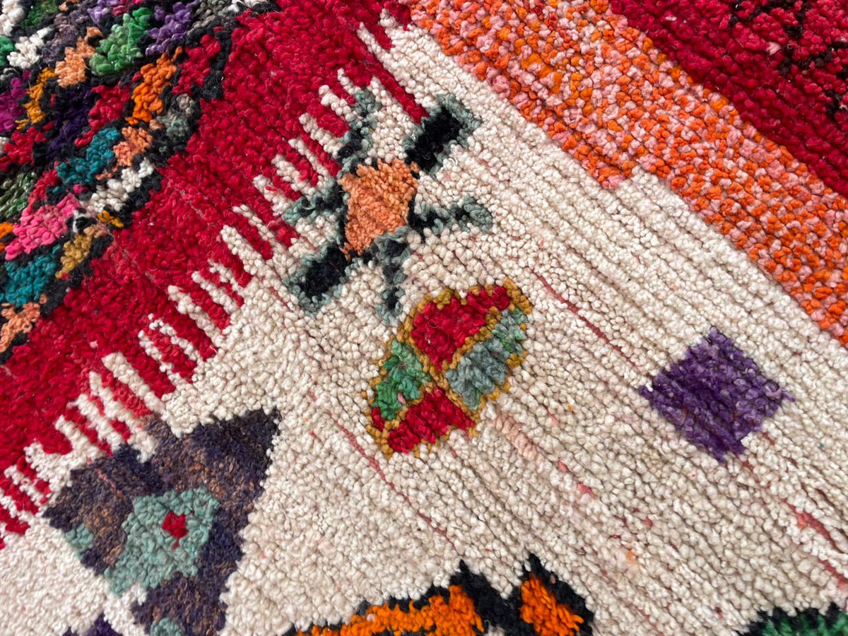Detail close-up of a vintage Moroccan rug featuring abstract shapes in red, orange, purple, and white.