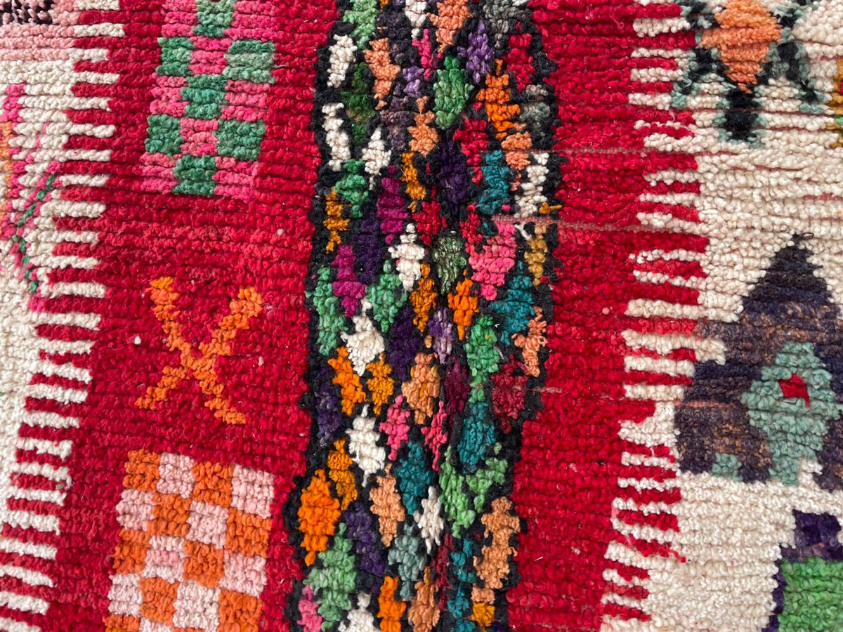Detail close-up of a vintage Moroccan rug showcasing colorful patterns in red, cream, and blue.