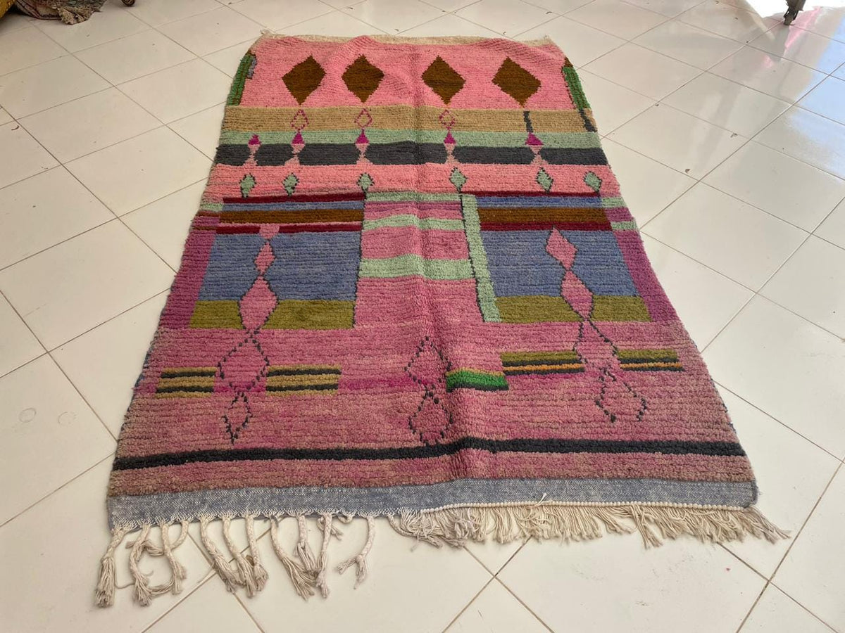 Front view of a pink vintage Moroccan rug showcasing geometric patterns on a white background.