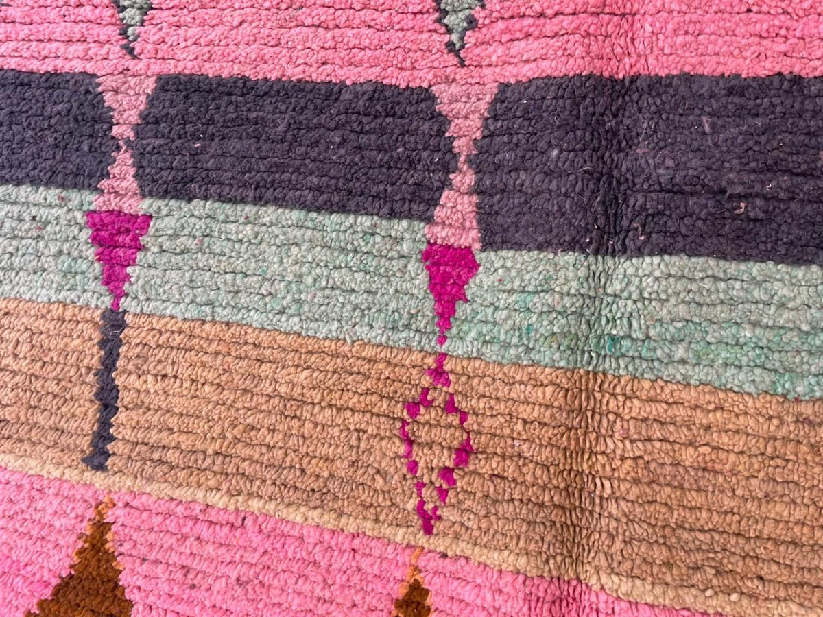 Detail close-up of a pink vintage Moroccan rug highlighting colorful patterns and textured fabric.