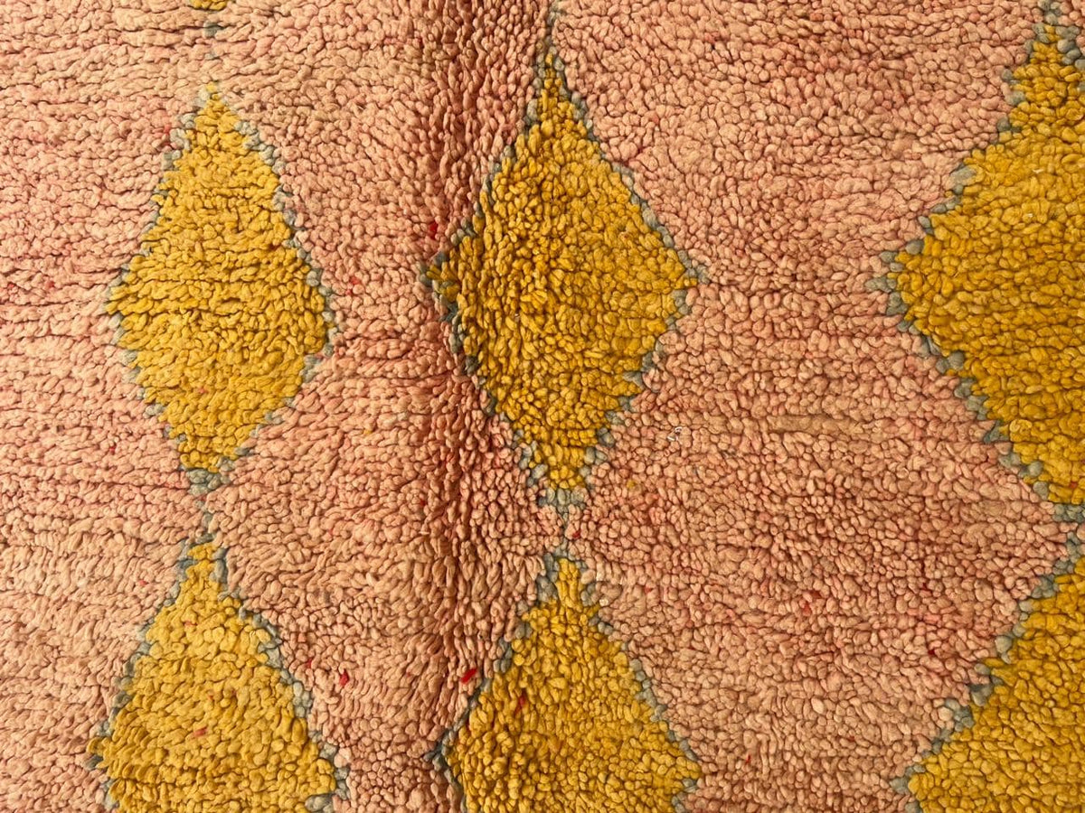 Detail shot highlighting the soft texture and diamond shapes of the pink vintage Moroccan rug.