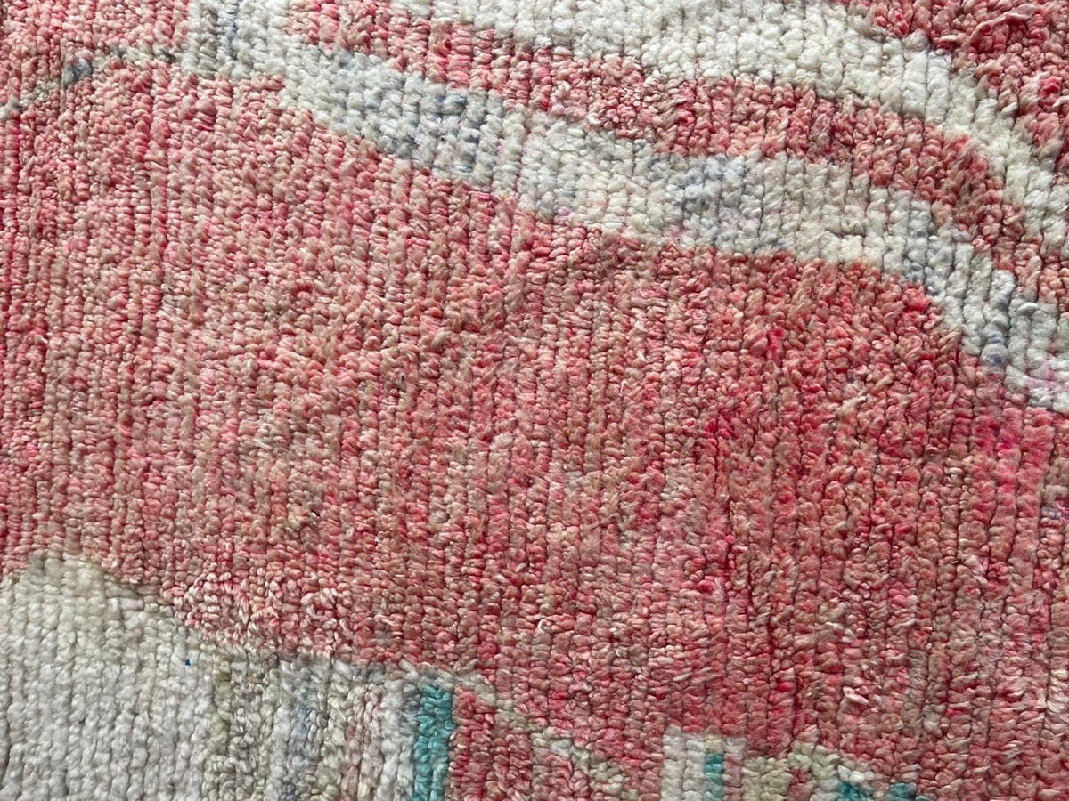 Close-up detail of the intricate pattern on a pink vintage Moroccan rug with colorful sections.