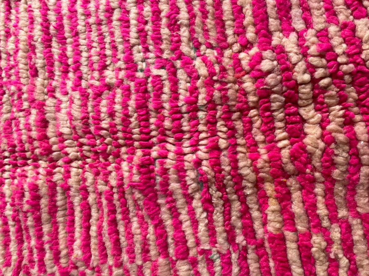 Close-up detail of a pink vintage Moroccan rug highlighting its textured surface and fringe edges.