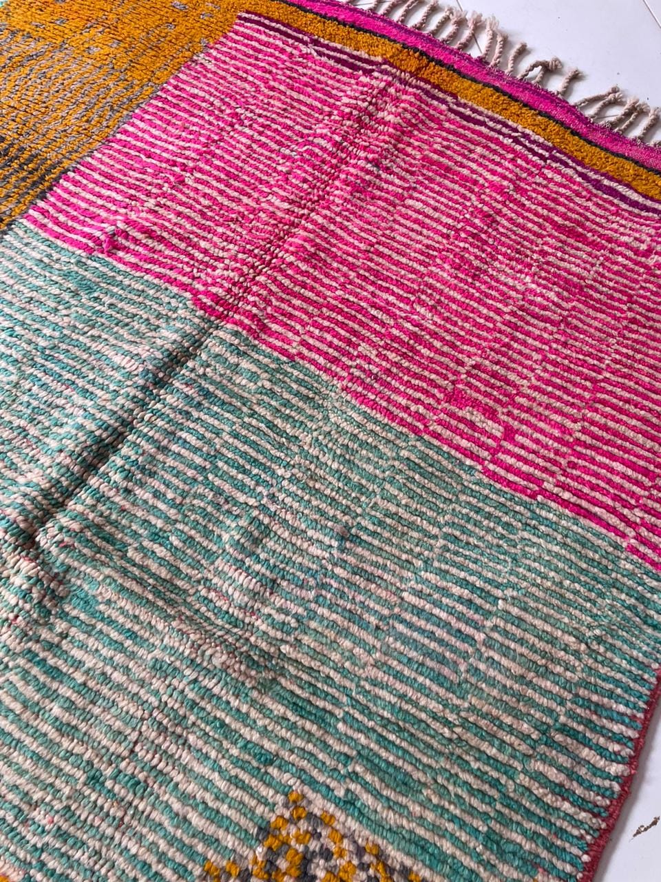 Close-up detail of a vintage Moroccan rug showcasing an intricate pattern and fringed edges.