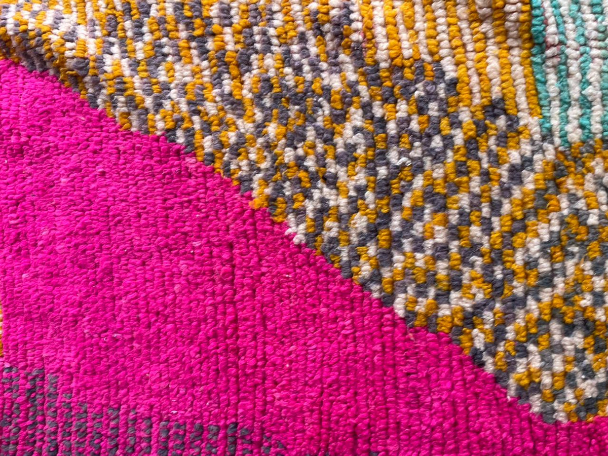 Close-up detail of a vintage Moroccan rug featuring colorful patterns and a textured surface.