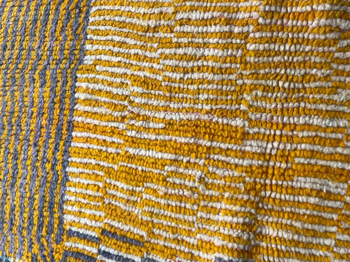 Close-up detail of a vintage Moroccan rug with a striped pattern in yellow and blue.