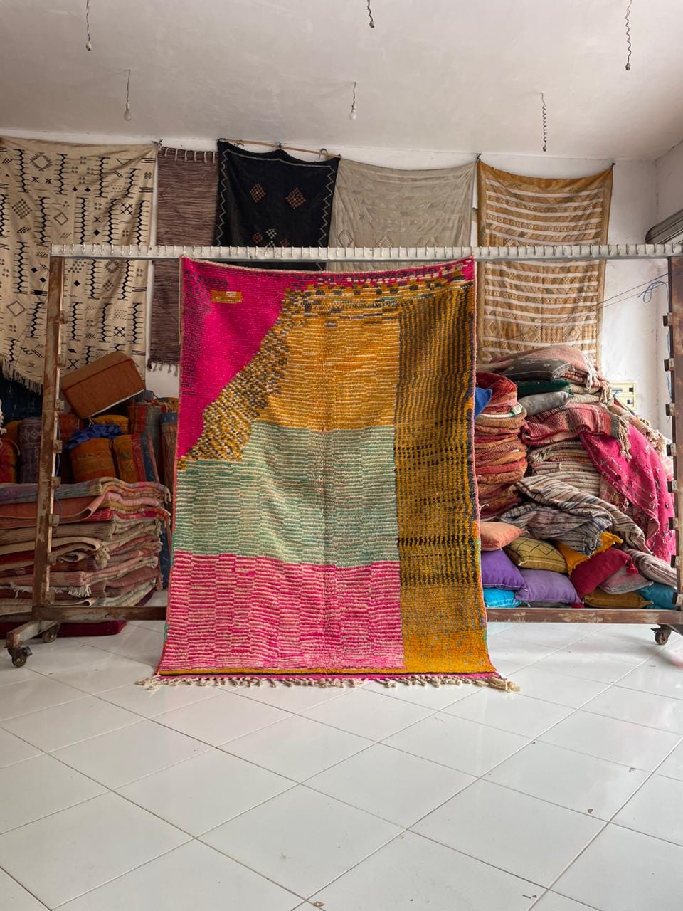 Lifestyle view of a pink vintage Moroccan rug with geometric patterns and fringe edges.