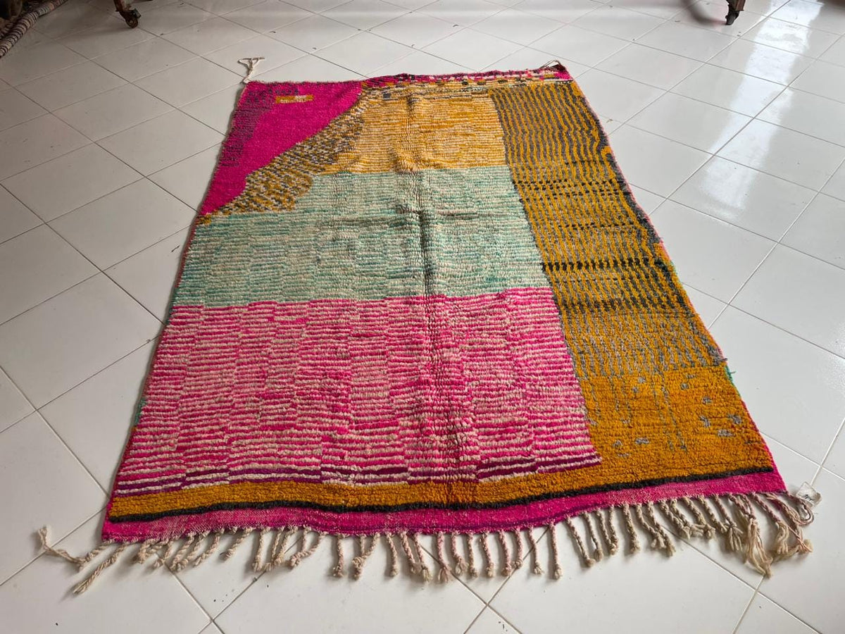 Close-up detail of a pink vintage Moroccan rug showcasing its textured surface and fringe edges.