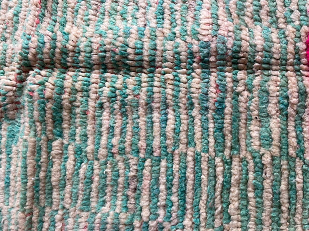 Close-up detail of a pink vintage Moroccan rug displaying a striped pattern.