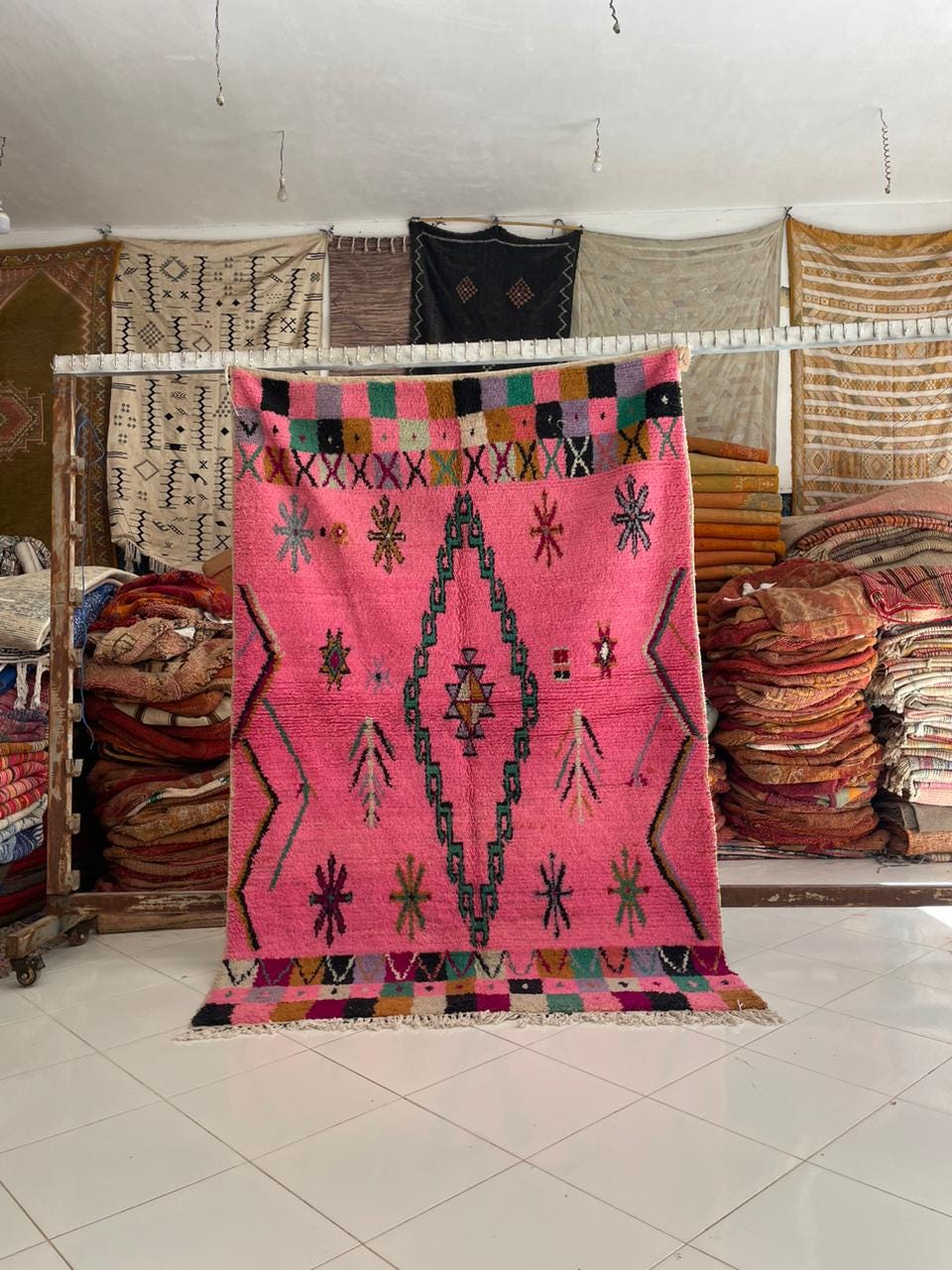 Lifestyle shot of a pink Moroccan rug featuring geometric patterns and fringe edges.