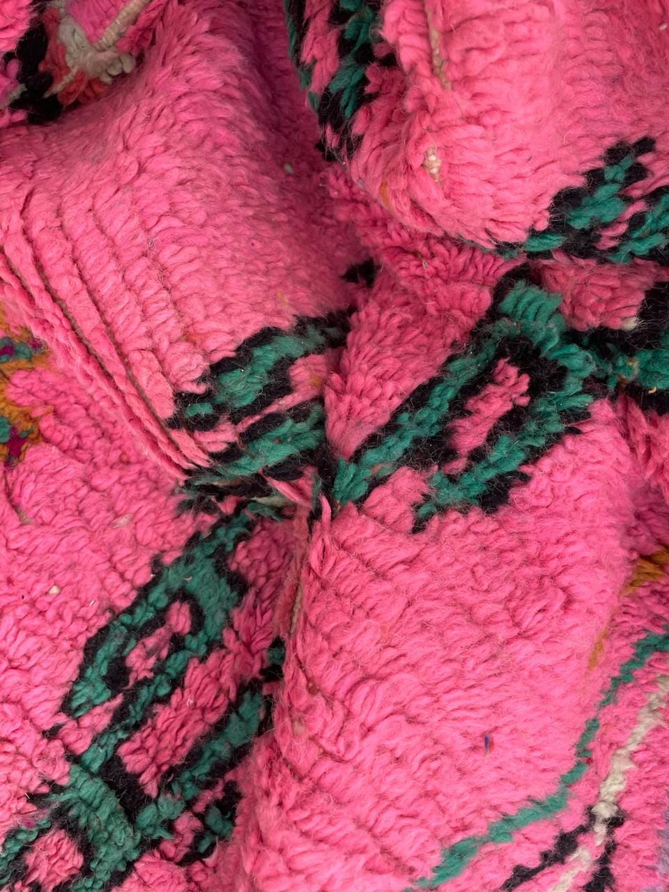 Detail close-up of a pink Moroccan rug featuring an abstract design and soft texture.