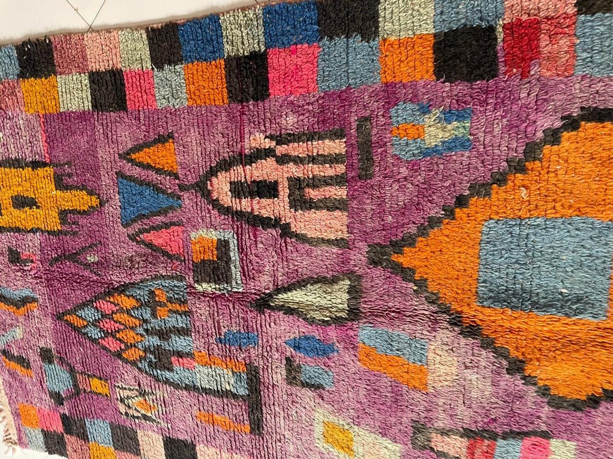 Close-up detail of a vintage Moroccan rug with colorful patterns and textured surface.