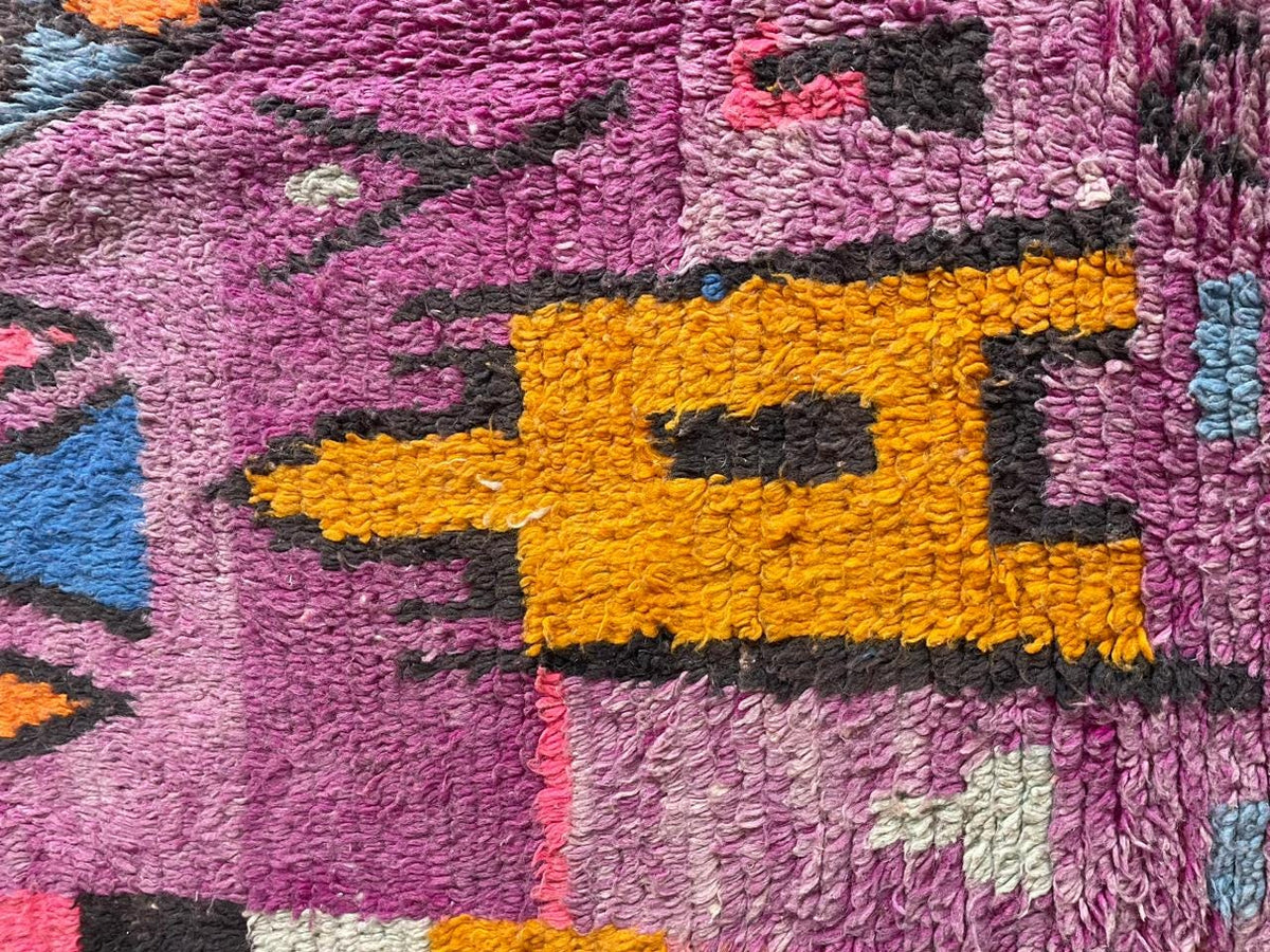 Close-up detail of geometric patterns and texture on a vintage Moroccan rug in purple and black.