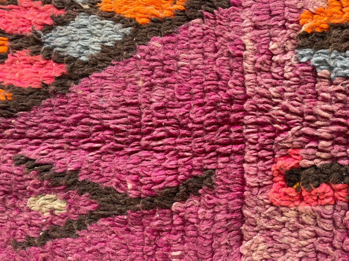 Close-up detail of abstract designs on a vintage Moroccan rug in purple and gray.