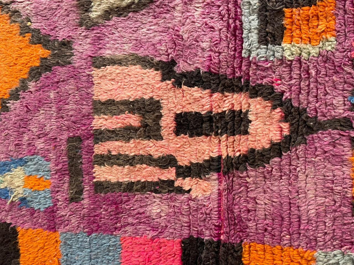 Close-up detail of geometric patterns on a vintage Moroccan rug in purple and black.