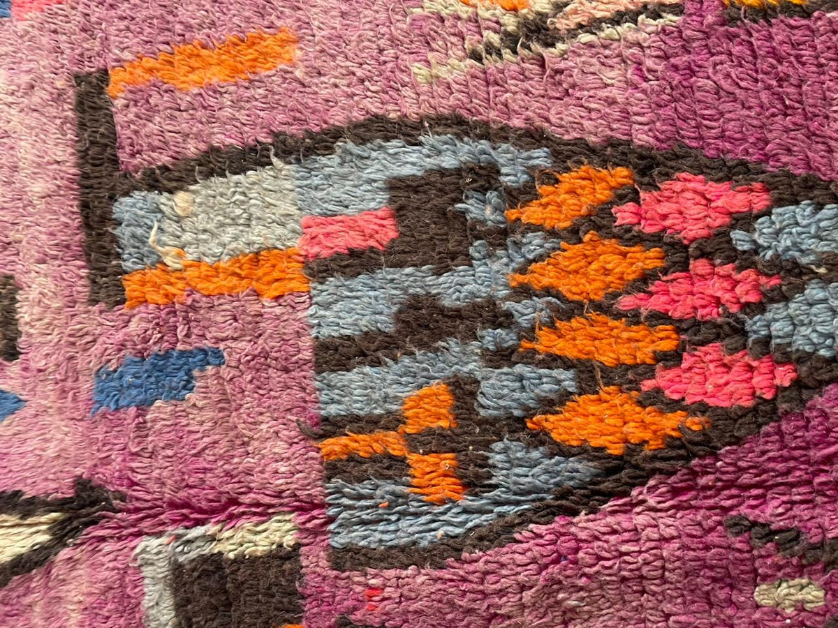 Close-up detail of intricate designs on a vintage Moroccan rug in purple and orange.