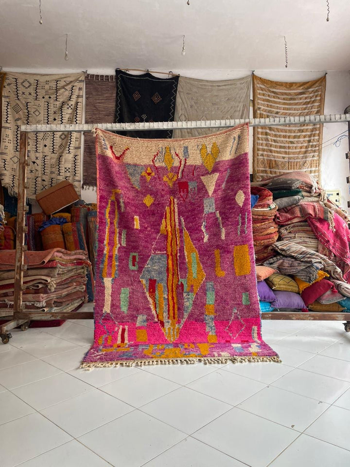 Lifestyle shot of a vintage Moroccan rug featuring geometric patterns in purple and pink.