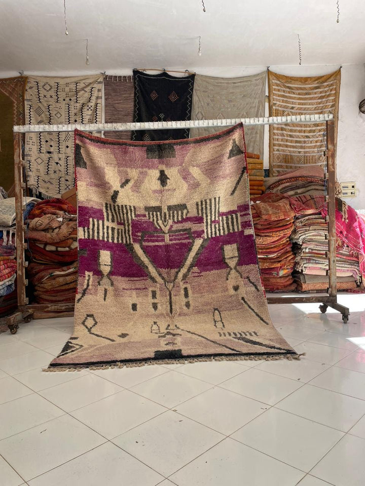 Lifestyle shot of a vintage Moroccan rug featuring geometric patterns in purple and beige.