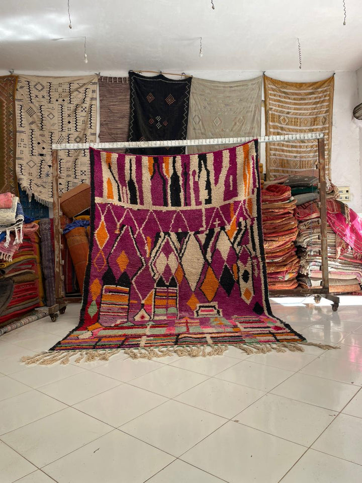 Lifestyle shot of a vintage Moroccan rug featuring geometric patterns in purple and orange.